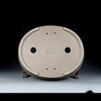 Underside of the taupe oval pot with two drainage holes and smaller openings