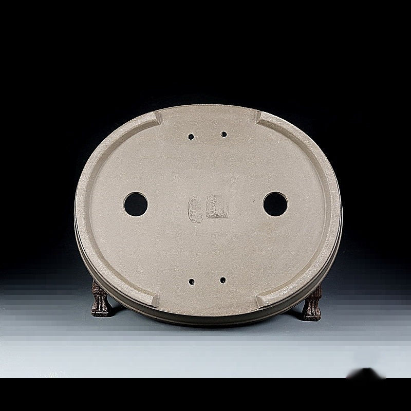 Underside of the taupe oval pot with two drainage holes and smaller openings