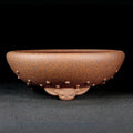 Speckled brown round pot with raised studs and curled decorative feet