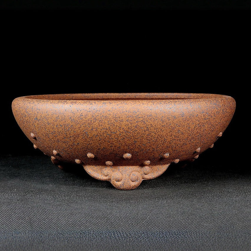 Speckled brown round pot with raised studs and curled decorative feet