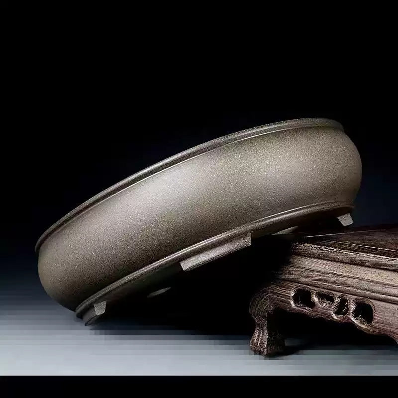 Taupe oval pot with rounded body tilted on a wooden stand