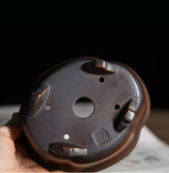 Underside of lobed pot showing central opening, feet and stamped mark
