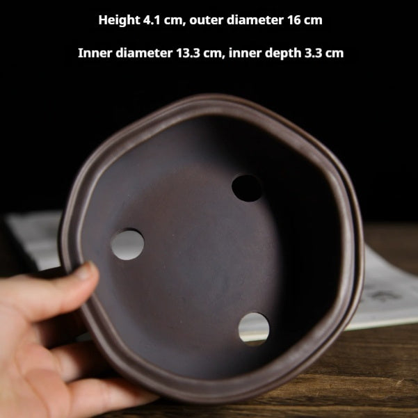 Top view of dark brown irregular pot showing three large openings and small holes