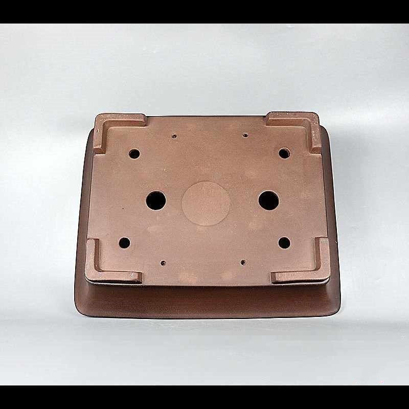 Underside of brown rectangular pot showing openings and corner feet
