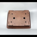 Underside of brown rectangular pot showing openings and corner feet