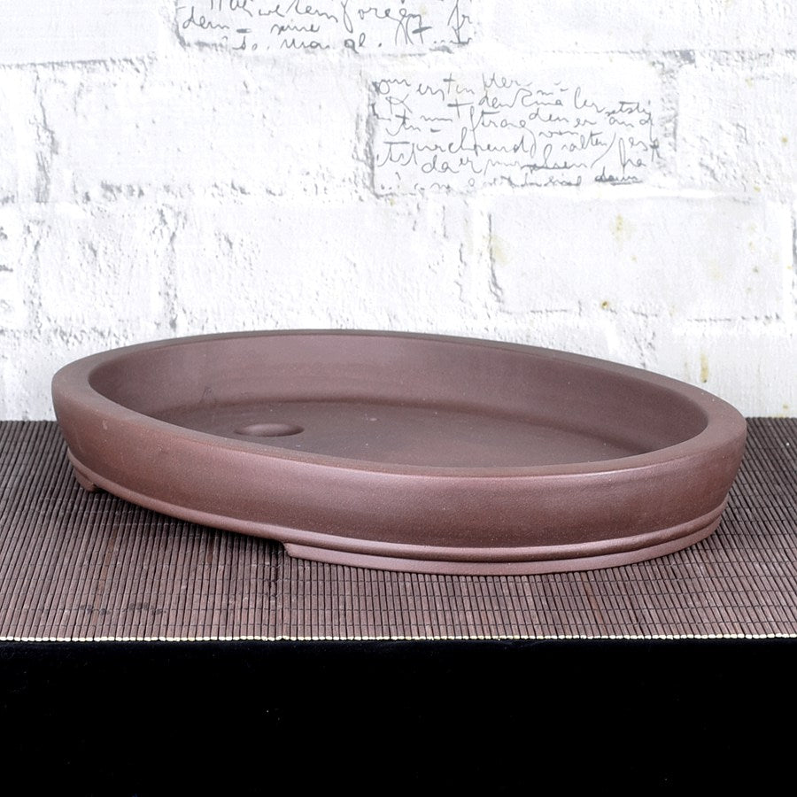 Angled view of shallow brown oval bonsai pot showing interior