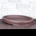 Angled view of shallow brown oval bonsai pot showing interior