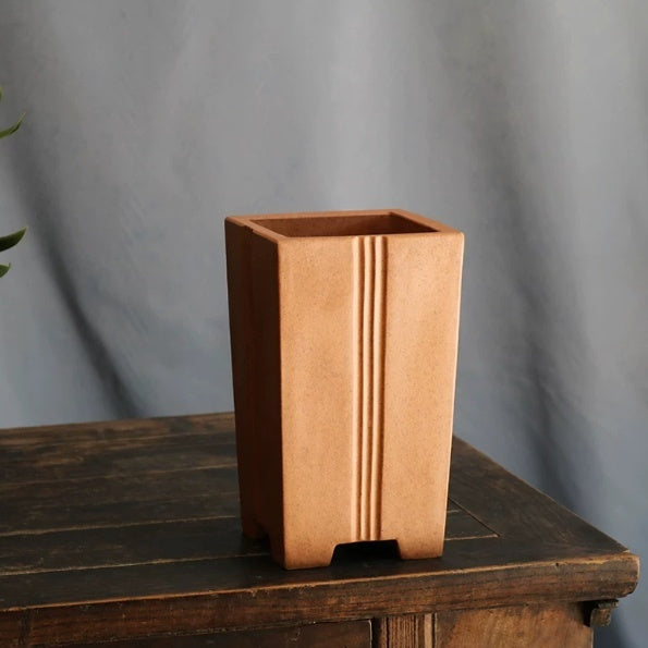 Angled tall ochre square pot showing open rim and vertical grooves