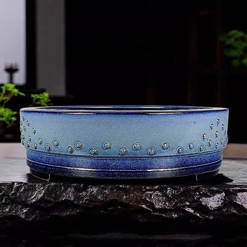 Blue studded drum pot displayed on a dark stone slab