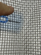 Close-up of coarse square sieve mesh beside a ruler