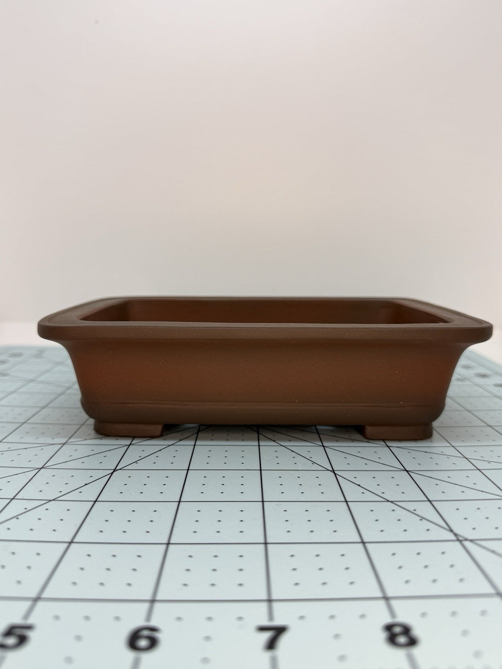 Low front view of the brown pot showing its shallow body and raised rim