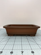 Low front view of the brown pot showing its shallow body and raised rim