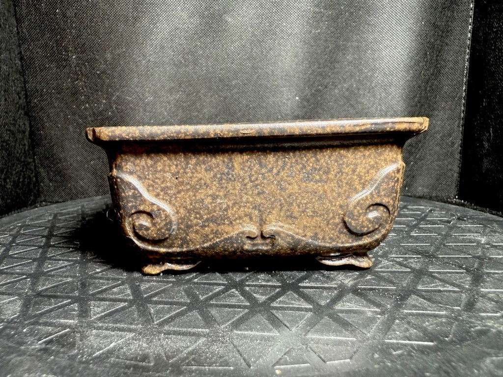 Angled side view of the mottled brown rectangular pot with curled relief decoration