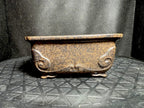 Angled side view of the mottled brown rectangular pot with curled relief decoration