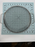 Overhead view of a round handled metal sieve on a measuring grid