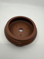 Angled interior view of the brown pot with one central drainage hole and three smaller openings