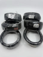Six wrapped black wire coils arranged in two groups on a white surface