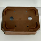 Close underside view of the brown pot with two drainage holes and four smaller tie-down openings