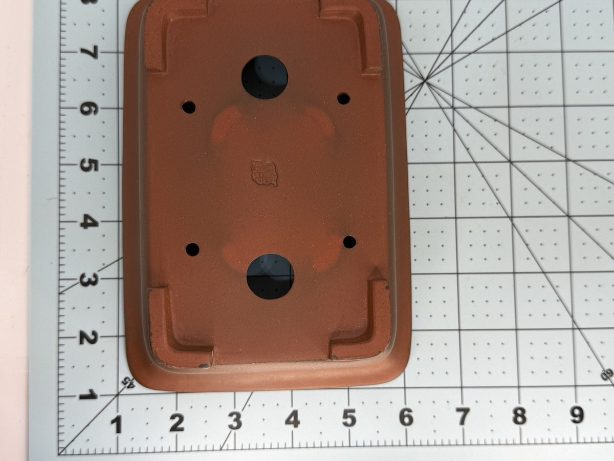 Overhead view of the brown pot's base on a measuring grid