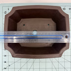 Overhead view of a ruler spanning the dark pot's interior opening