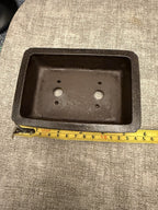Dark rectangular pot photographed with a tape measure along its exterior length