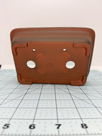 Underside of the brown rectangular pot showing two drainage holes, four smaller openings and corner feet