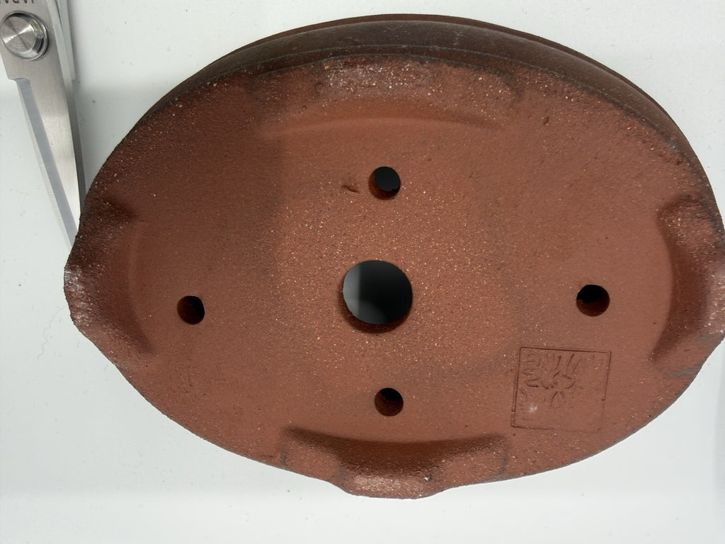 Underside of the starter kit's brown oval pot showing one central drainage hole and four smaller openings