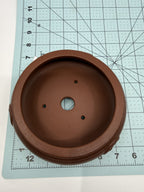 Overhead view of the brown pot's opening and drainage holes on a measuring grid