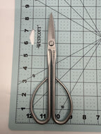 Long silver bonsai scissors laid on a numbered measuring mat