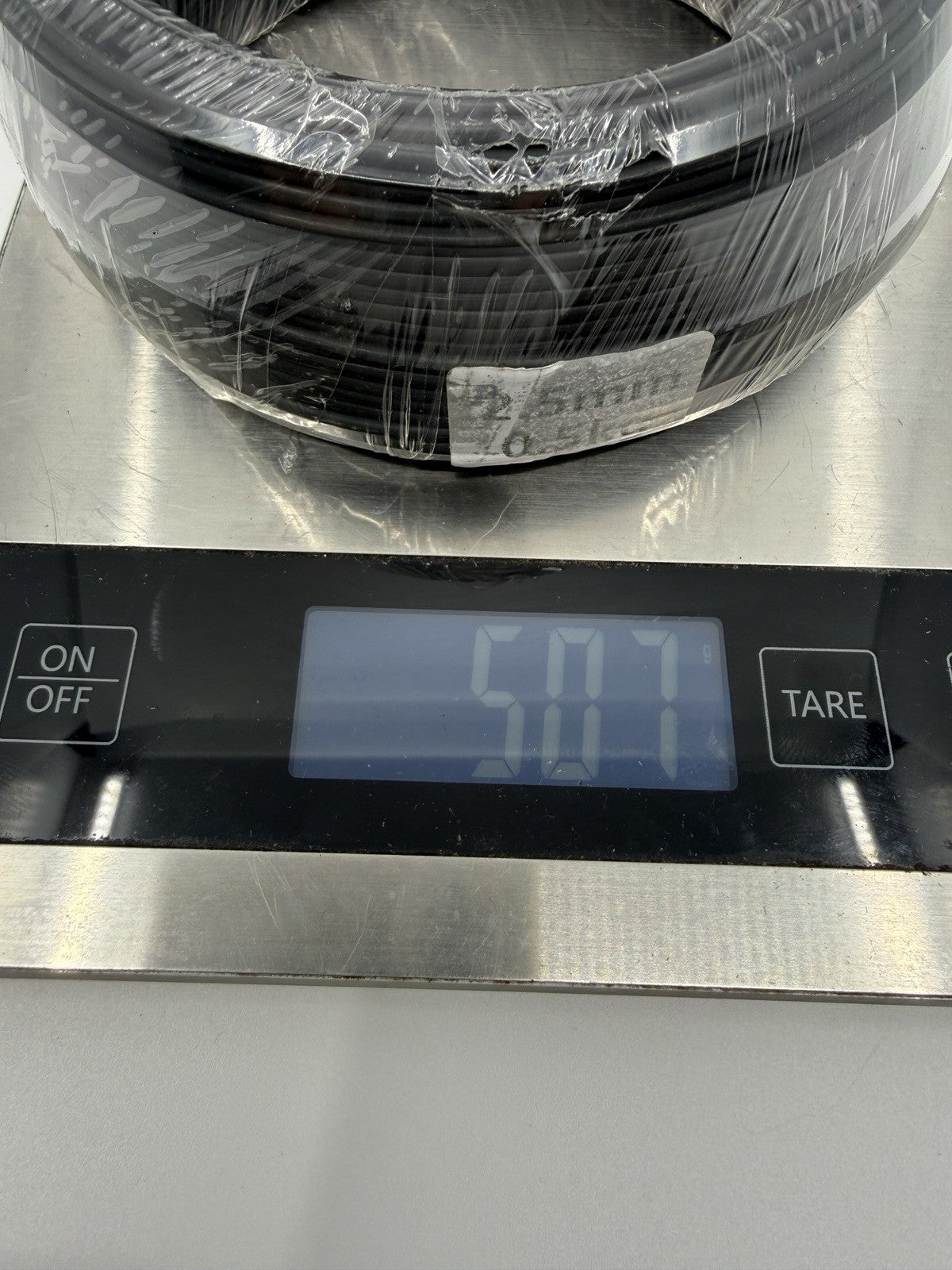 Close-up of wrapped black wire coils on a digital scale with the display visible