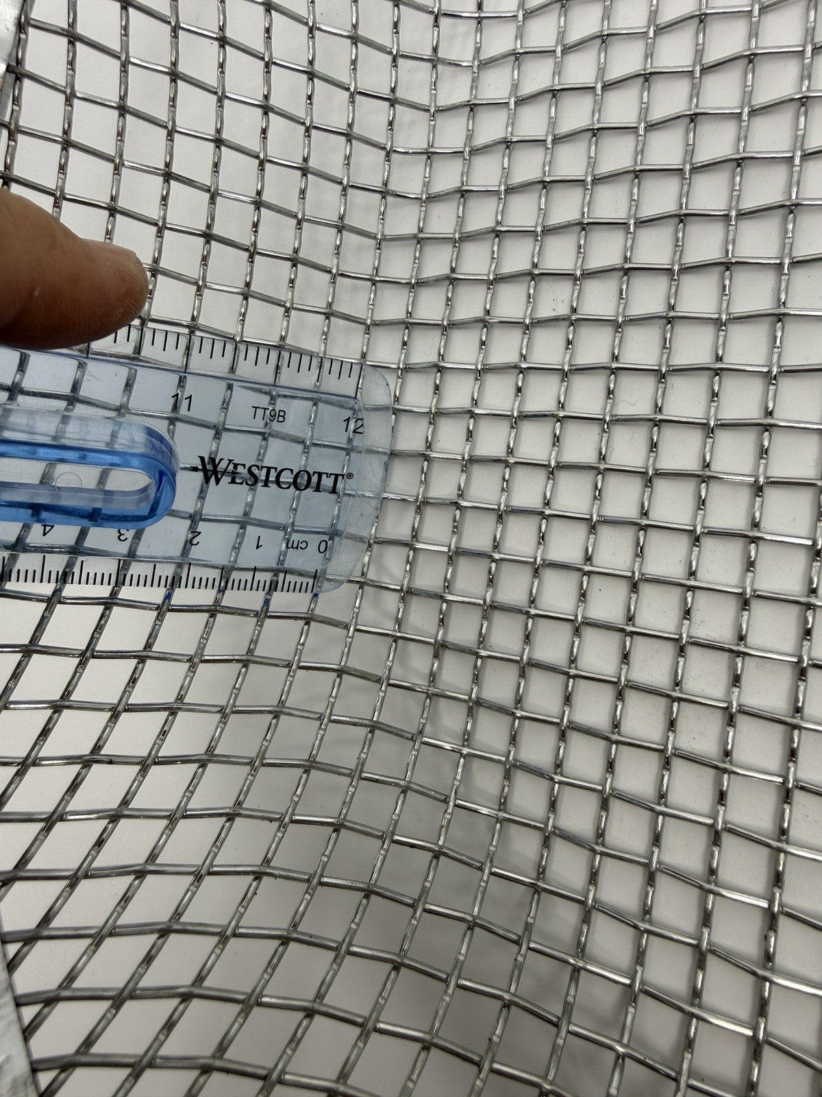 Close-up of finer square sieve mesh beside a ruler