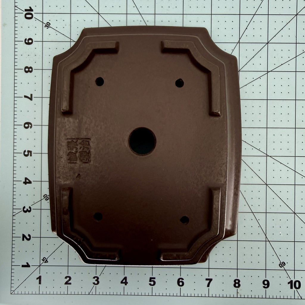 Base of the dark rectangular pot on a measuring mat, showing its seal and drainage holes