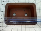 Ruler spanning the brown rectangular pot's interior opening