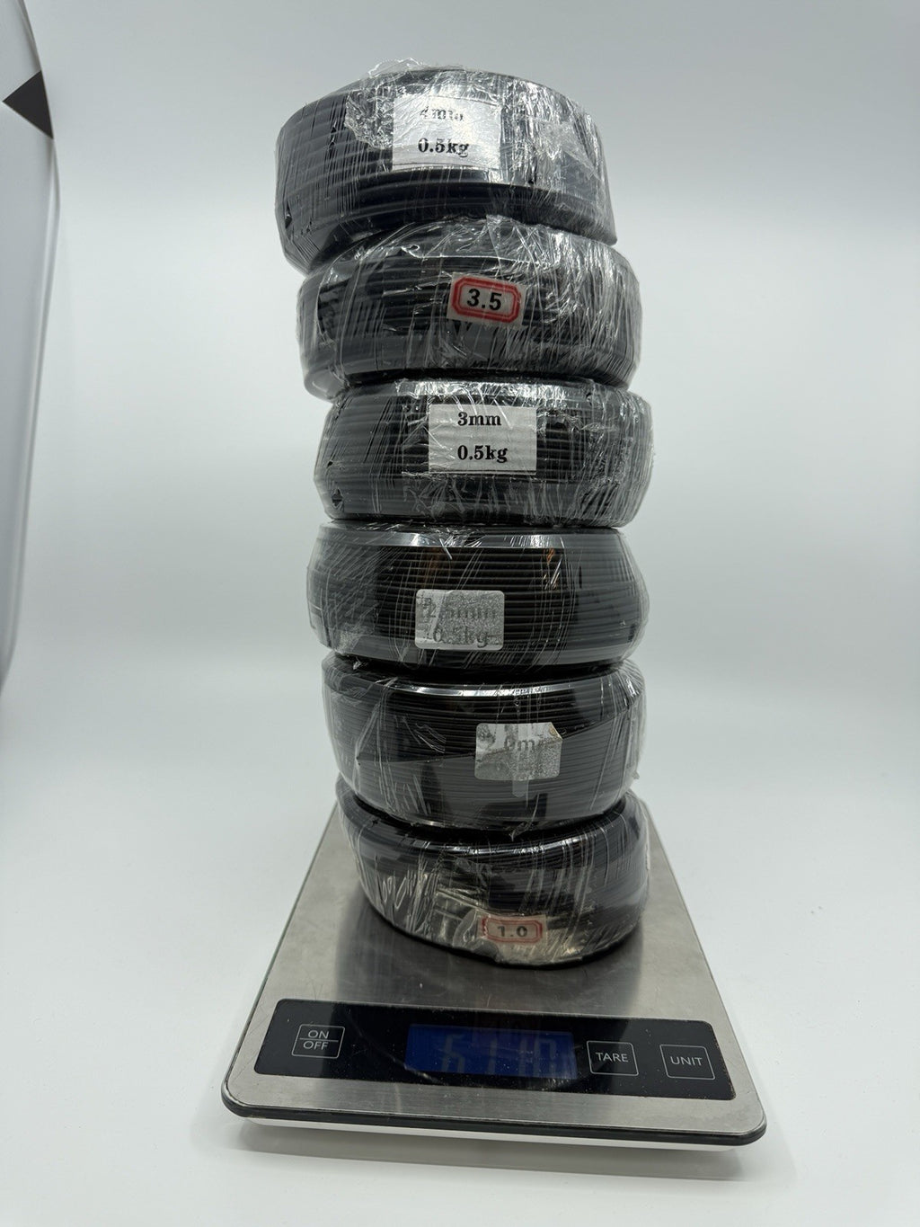 Six black wire coils stacked vertically on a digital kitchen scale