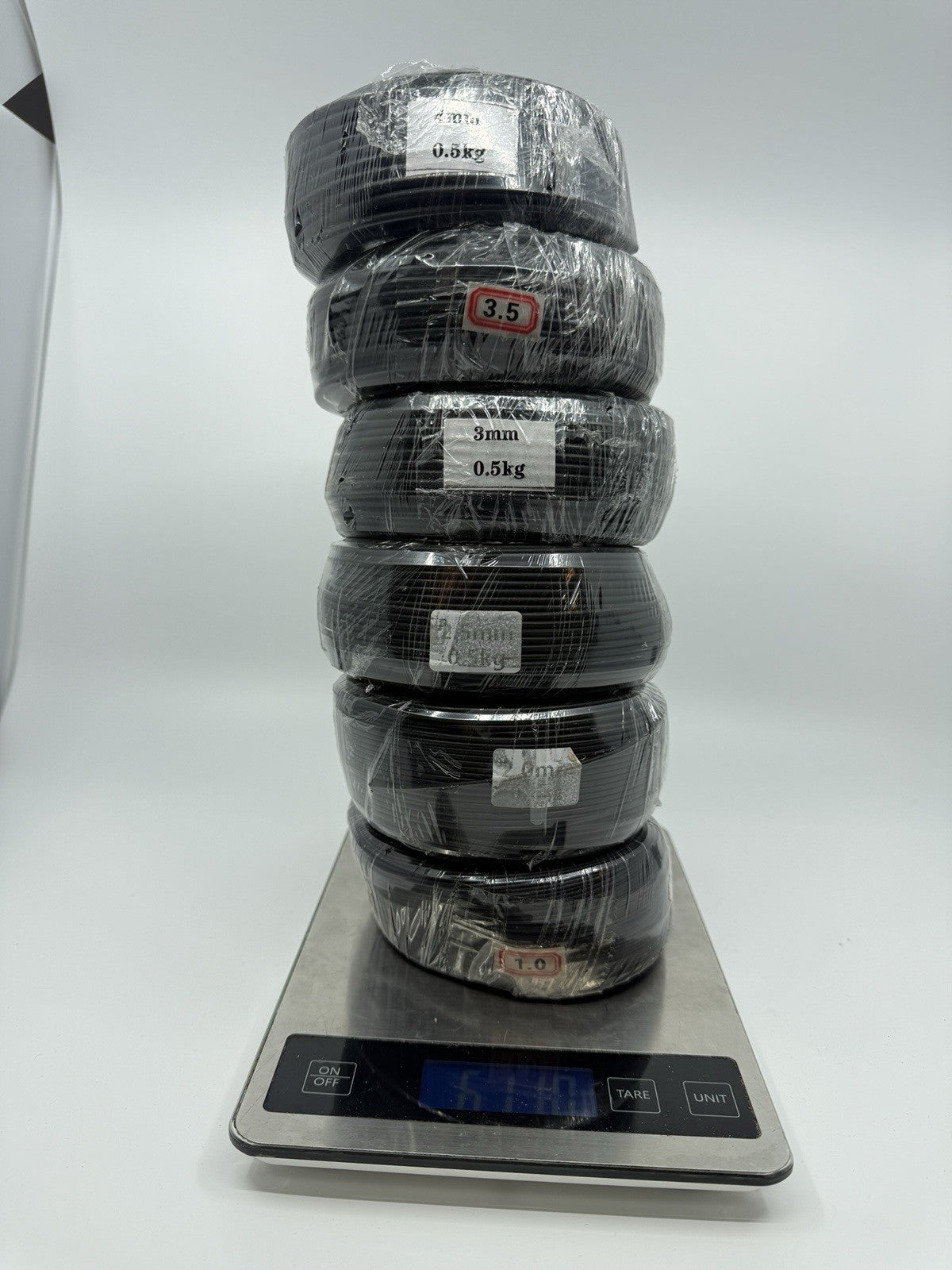 Six black wire coils stacked vertically on a digital kitchen scale