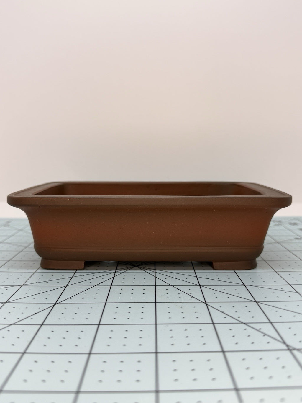 Long-side view of the brown rectangular pot on a gridded measuring mat