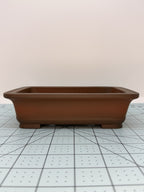 Long-side view of the brown rectangular pot on a gridded measuring mat