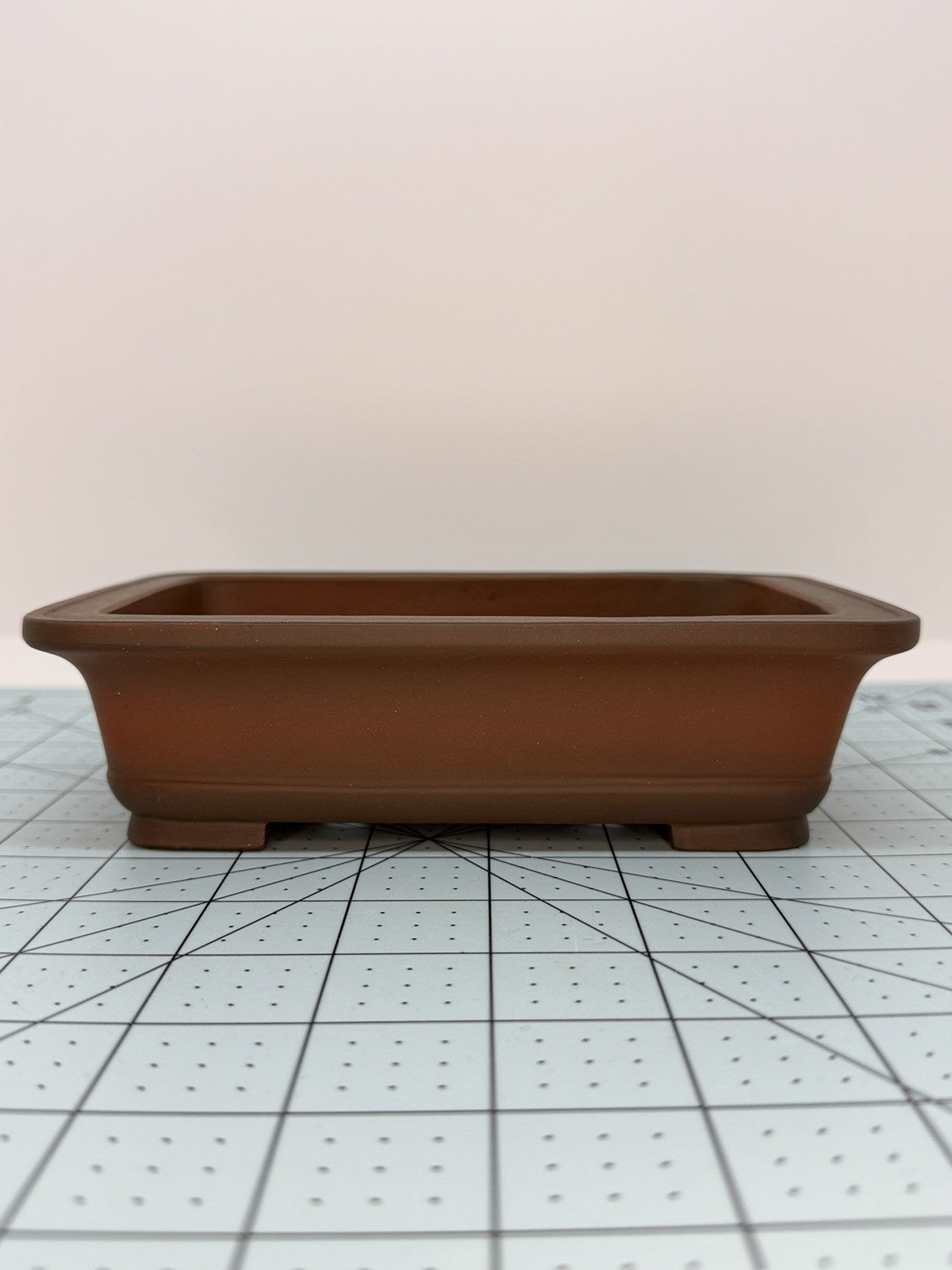 Long-side view of the brown rectangular pot on a gridded measuring mat