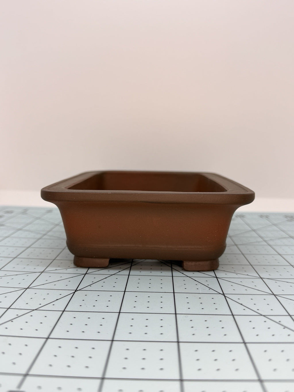 Short-side view of the brown rectangular pot showing its flared rim and block feet