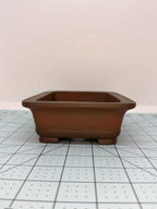 Short-side view of the brown rectangular pot showing its flared rim and block feet