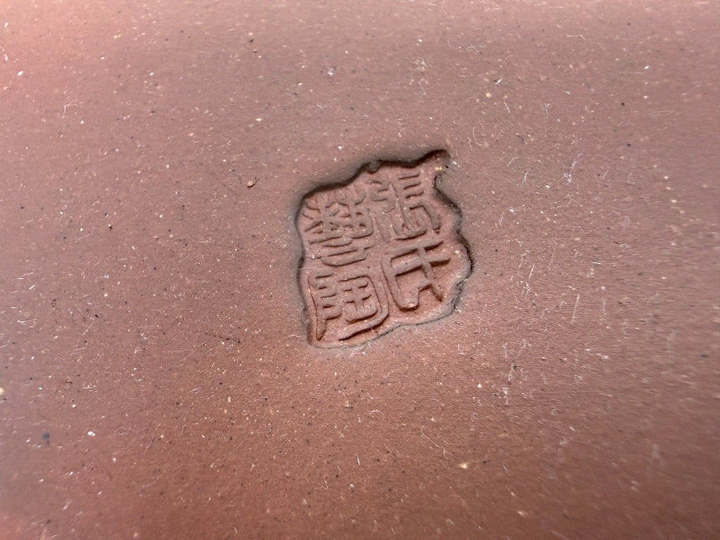Close-up of the impressed square seal in the brown pot's clay base