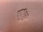 Close-up of the impressed square seal in the brown pot's clay base