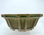 Front view of the olive-green flower pot with darker glaze accents along the rim and feet