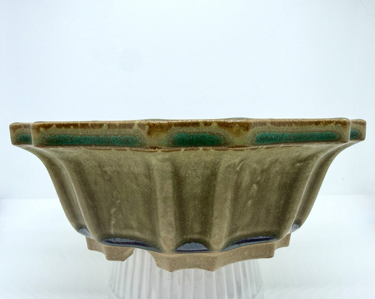 Front view of the olive-green flower pot with darker glaze accents along the rim and feet
