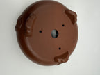 Tilted underside view of the brown pot with three decorative feet and a central drainage hole