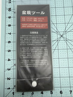 Back of a bonsai tool package showing printed specifications and instructions on a measuring mat