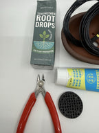 Close-up of Root Drops packaging, red-handled cutters, mesh disc and brown pot