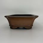 Front view of the brown rectangular pot showing its flared rim and band above the feet