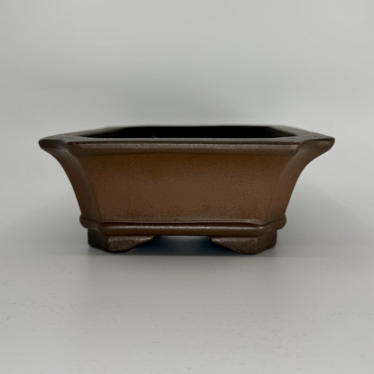 Front view of the brown rectangular pot showing its flared rim and band above the feet