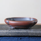 Side view of red-brown lobed bonsai pot on decorative feet